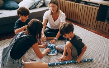 Mother and children wrapping gifts together, enjoying quality family time indoors.